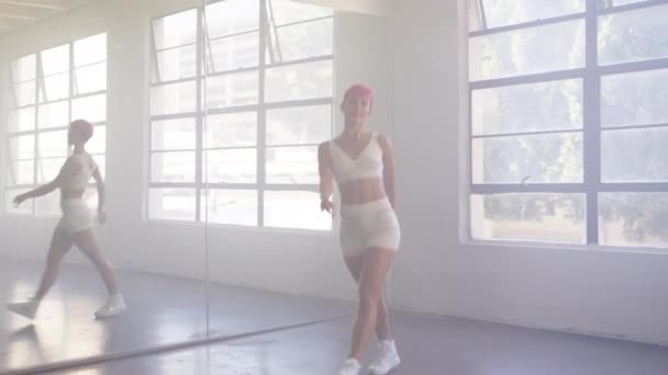 短いピンクの髪を持つセクシーな自信に満ちた若い女の子が積極的にミラーウォールスタジオで踊ります 美しいヒップスター千年の先生のプロのダンストレーナーが示す現代的な動きとダンスクラス4K映像 — ストック動画