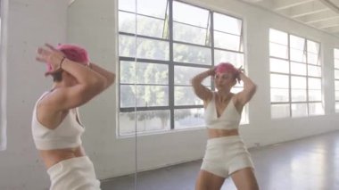 Professional instructor training combo for dance class group in studio. Beautiful woman dancing in front of mirror wall, enjoying workout practicing modern choreography moves for show performance 4K