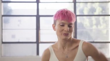 Portrait young woman professional dance trainer performing beautiful modern dance combo with active hands, shoulders and head movements. Attractive girl with pink hair flirting looking straight camera