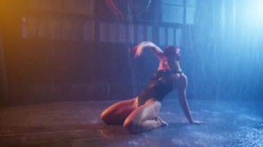 Woman dancing on wet floor under pouring water rain, performing sexy moves by fit wet body. Sensual adult woman shows wide opened stretched legs 4K. Erotic performance in privat room of strip club