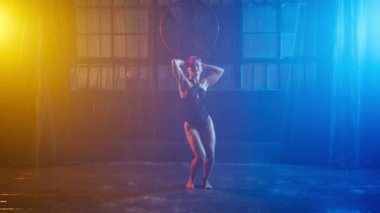Erotic dance of seductive girl with sexy body. Silhouette of sexy woman performing under pouring rain in glowing beams of yellow and blue spotlights on urban grunge futuristic cyberpunk background 4K