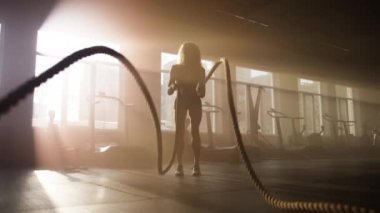 Aktif, sportif bir kızla çalışma ilham veren bir duvar kağıdı. Dinamik egzersizler yaparken savaş halatları kullanan kararlı sporcunun yakın plan çekimi. Yüksek kalite 4k görüntü