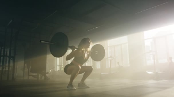 年轻的 高加索女运动员蹲在室内 重量轻 一个活跃的金发运动员和一个杠铃一起锻炼的特写 高质量的4K镜头 — 图库视频影像