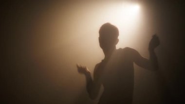 Minimalist monokrom sepia renginde dans eden kadın silueti. RED kamerada ağır çekimde sanat konsepti. Arka planda poz veren gölgeli seksi kadın. Sanatsal dansçı erotik muhteşem dans yapıyor.