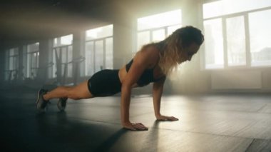 Close-up shot of a beautiful girl performing push-ups in modern gym studio. Portrait of caucasian woman in a good shape exercising alone. High quality 4k footage