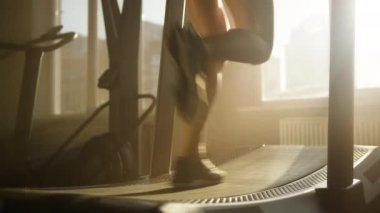 Slim female legs running on treadmill machine during intensive CrossFit training. Close-up shot of a woman improving her endurance and strength while working out in gym studio. High quality 4k footage