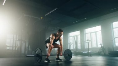 Portrait of caucasian man in black sportswear exercising indoors. Close-up view of sporty, young bodybuilder lifting a barbell with loaded heavy weights. High quality 4k footage