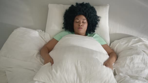 抑郁症或精神健康问题突发 从上往下看年轻的非洲裔美国女人躺在床上 用大枕头捂住脸 遮掩现实 不想看到光明 不想醒来 — 图库视频影像