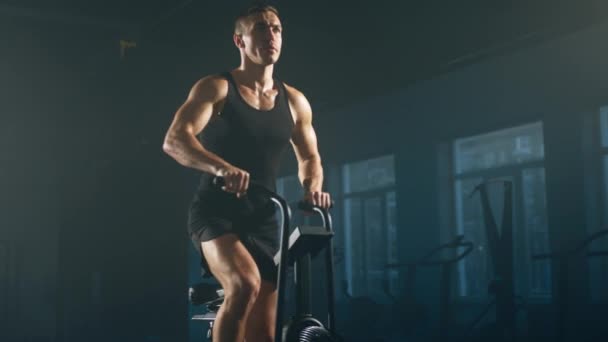 黒のスポーツウェアの男性選手のクローズアップビューは カロリーの多くを燃焼 献身的で活発な男の肖像は楕円形のトレーナーに彼の心臓能力を高める 高品質4K映像 — ストック動画
