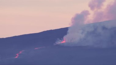 Distance shot on RED camera of hot red lava in fissure splashing high with dangerous smog. Mauna Loa mountain eruption with magma fountain, Hawaii Big Island in Pacific ocean.Outdoor nature wanderlust