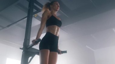 Close-up view of female athlete using pull up bar to build impressive upper-body muscle in loft-styled gym studio. Portrait of blonde sportswoman in training her triceps. High quality 4k footage