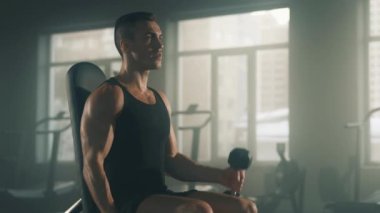 Close-up shot of active sportsman training his biceps in empty gym in the morning. Portrait of active man having weight workout to tone his muscles. High quality 4k footage