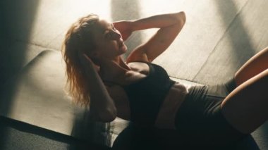 Portrait of dedicated, caucasian sportswoman doing crunches to build abdominal muscles. Close-up view of sporty, blonde-haired girl gaining athletic body in the gym. High quality 4k footage