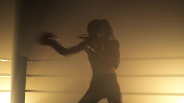 若い女性が攻撃を練習し ボクシングリングのばねの前に暖まるのクローズアップビュー スプリングの前にボクシングの手袋の訓練の女性のボクサーの肖像画 高品質4K映像 — ストック動画