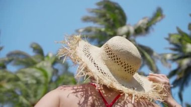 Traveler tourist woman in stylish straw hat relaxing on summer vacation at paradise island. Happy holiday at luxury hotel tropical resort USA. Enjoying summer tourism, ocean beach with green palms 4K