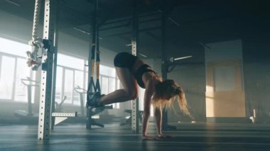 Close-up view of caucasian woman training abs with a suspension trainer indoors. Portrait of dedicated sportswoman improving total-body strength, stability and heart health. High quality 4k footage