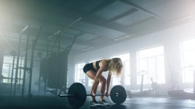 Portrait of caucasian, sporty woman lifting weights to burn calories for weight loss. Close-up view of female athlete using a barbell during a powerlifting workout. High quality 4k footage