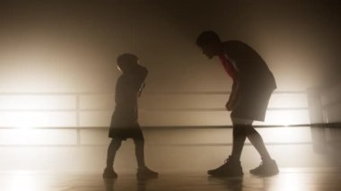 Close-up shot of adult man teaching young sportsman to attack and protect himself. Portrait of sparring between coach and little athlete. High quality 4k footage