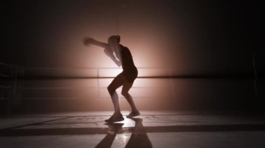 Close-up shot of female boxer boosting whole-body strength with a spotlight in the background. Portrait of a sportswoman exercising to improve her shape and build muscles. High quality 4k footage