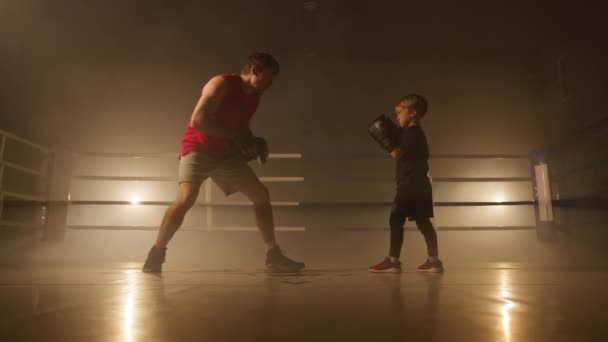 一个自信 活泼的孩子在拳击赛中与教练打斗的形象 一个身披皮手套 身手敏捷的男孩正在进行特写 以训练他的耐力 高质量的4K镜头 — 图库视频影像