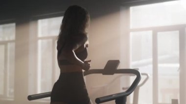 Female legs during cardio workout session in modern, empty gym club. Portrait of active, muscular woman in black sportswear running to improve her endurance. High quality 4k footage