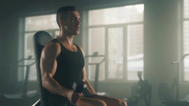 Portrait of caucasian man practicing dumbbell curls to gain lean muscles. Close-up shot of active sportsman training his biceps in empty gym in the morning. High quality 4k footage