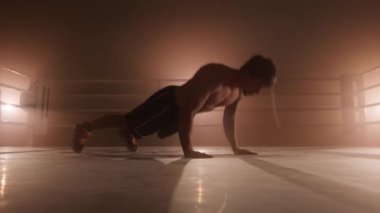 Close-up shot of professional boxer pushing up and clapping behind his back. Portrait of a male athlete boosting his stamina and endurance while preparing for a sparring. High quality 4k footage