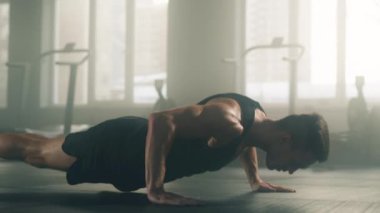Close-up view of a focused athlete in black sportswear performing barbell curls exercises. Portrait of caucasian man practicing push-ups to gain lean muscles. High quality 4k footage
