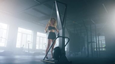 Close-up shot of a sweating, tired female athlete having intensive workout indoors. Portrait of caucasian, sporty woman pulling weights to burn calories for weight loss. High quality 4k footage