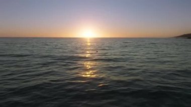 Picturesque paradise island coast, washed with calm and tranquil tides. Cinematic, colorful skyline over the deep ocean waters and sun setting behind the horizon. High quality 4k footage