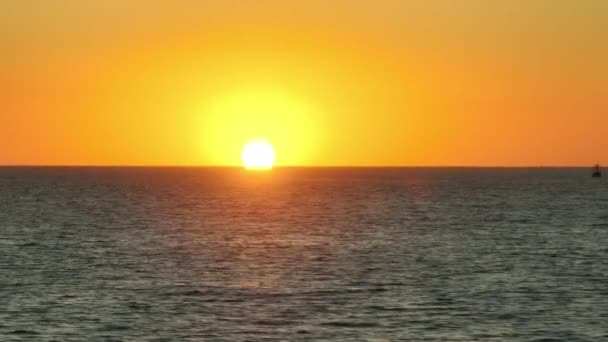 カラフルな地平線の後ろに明るい太陽が沈む大規模で穏やかな海の水のパノラマ 海岸から見た雄大な黄金の時間で穏やかな海のドローンショット 高品質4K映像 — ストック動画