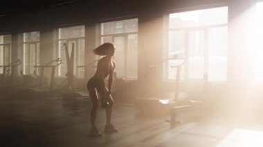 Close-up shot of female athlete using weights to gain lean, healthy body and strong muscles. Portrait of a woman lifting heavy dumbbell in gym studio. High quality 4k footage