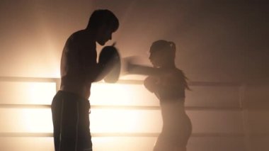 Portrait of a couple training before the championship match. Close-up shot of a woman working out with a personal trainer in the boxing ring. High quality 4k footage