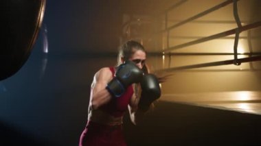 Close-up view of young and confident girl practicing her kick in boxing gloves. Portrait of active, caucasian female athlete boosting her endurance in gym. High quality 4k footage