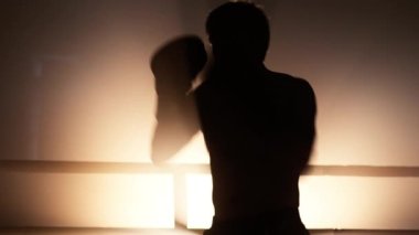 Close-up view of caucasian man in his 40s wearing boxing gloves. Portrait of professional boxer practicing his hit and warming up in the ring with spotlights around. High quality 4k footage