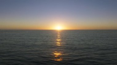Aerial view of idyllic holiday destination with picturesque ocean at sunset. Stunning panoramic view of colorful, sunrise skyline reflecting against water surface. High quality 4k footage