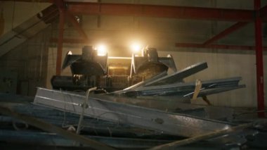 01 FEB. 2023. CALIFORNIA, USA. Working industrial machinery loading heavy metal pipes indoors. Footage of small track loader operating in a hangar. High quality 4k footage