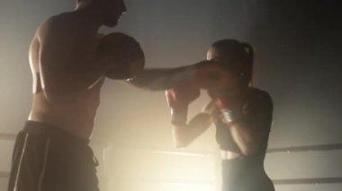 Portrait of professional kickboxers having intensive sparring indoors. Close-up shot of male and female athletes punching and kicking while training. High quality 4k footage