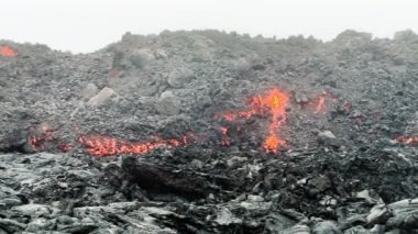 Panorama of steaming black lava rocks. Red hot molten lava flowing through streams on slope. Lava flow on Big Island in Hawaii, USA shot on smartphone camera. Volcano eruption on Mauna Loa mountain