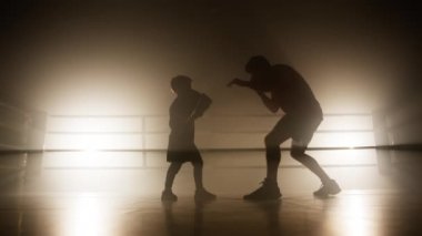 Aktif, yetenekli, boks eldiveni giyen ve antrenman yapan bir çocuğun portresi. Yetişkin bir adamın genç bir sporcuya saldırmayı ve kendini korumayı öğrettiği yakın çekim. Yüksek kalite 4k görüntü