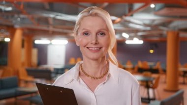 Portrait of happy smiling mature blonde businesswoman, small business owner, company leader or sales manager, female CEO executive. Headshot successful lawyer looking at camera standing in office 4K