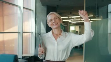 Smiling Mature Businesswoman 50s in eye glasses dancing walking at Office. Mature CEO Female Entrepreneur Happy, Joyful, having Fun at work getting big project successfully finished. Office concept 4K