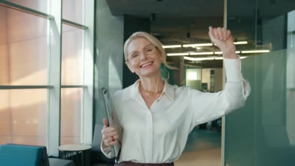 穿着眼镜跳舞的50多岁的职业女性在办公室里跳舞 成熟的首席执行官女企业家快乐快乐 让工作中的乐趣圆满完成大工程 办公室概念4K — 图库视频影像