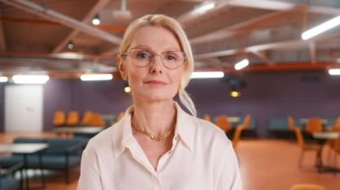 Confident beautiful mature 50s aged businesswoman professional in stylish eyewear executive manager, female lawyer or woman entrepreneur standing in office posing for headshot business leader portrait