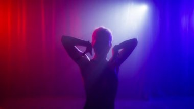 Şehvetli model kızın gölgesi yavaşça hareket eder ya da neon kırmızısı mor ışıkta dans eder. Dans eden elleri olan güzel seksi bir kadın vücudu. Stüdyoda kırmızı ve mavi ışık, moda çekimlerinde