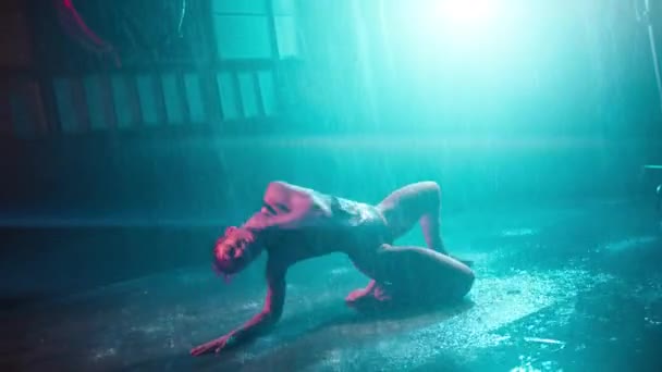 有诱惑力的女人在黑暗的网络朋克城市舞台上表演性感的脱衣舞娘 热火朝天的舞者坐在潮湿的地板上 在雨天电影车库的背景下 职业女子舞蹈家 — 图库视频影像