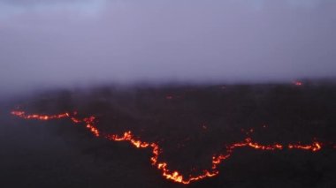 Pembe günbatımında, destansı sıcak kırmızı lav akışının üzerinde gökyüzünü kaplayan mor leylak bulutları. Sinematik çekim dumanı, tropik Hawaii Büyük Adası 4K 'da siyah donmuş lav tarlasının üzerinde güzel bir şekilde buharlaşıyor.