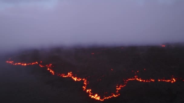 風光明媚なピンクの夕日で壮大な熱い赤い溶岩の流れの上に空を覆う紫色のライラック雲 熱帯ハワイの黒い氷結した溶岩原の上で美しく蒸発するシネマティックな空中ショット煙 Big Island — ストック動画