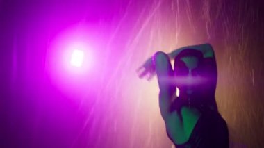 Renkli elleri ıslak kadının yağmurun altında ıslak vücuda dokunuşunun görüntüsü. 4K. Striptiz kulübünün özel odasında müşteriyi erotik dansla baştan çıkaran seksi kadın striptizci.