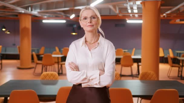 成熟的首席执行官领导女性 戴着眼镜 交叉着双臂 在公司阁楼办公空间的背景下看着相机 白种人50多岁成功 自信强的女经理女老板 — 图库视频影像